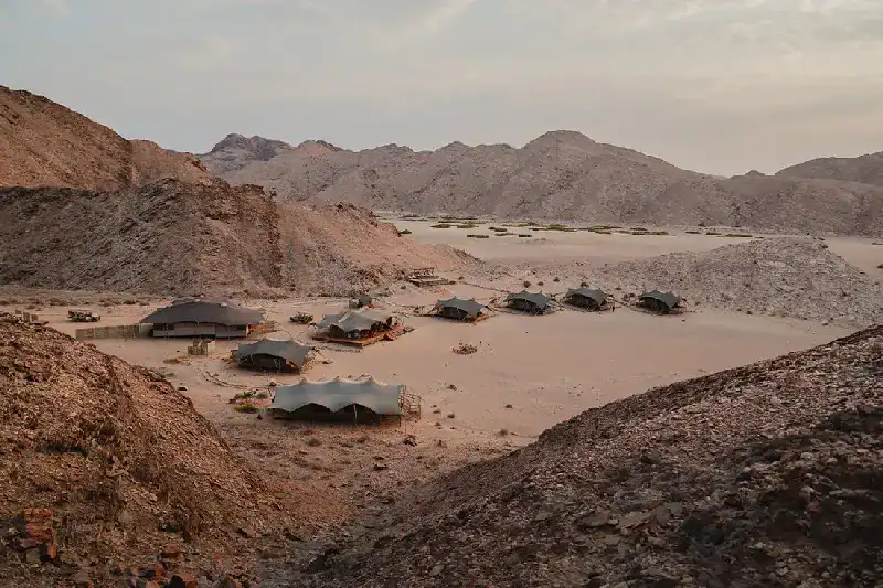 Hoanib Valley Camp's tented units set among rocky hills overlooking the dry Hoanib riverbed, Kaokoland